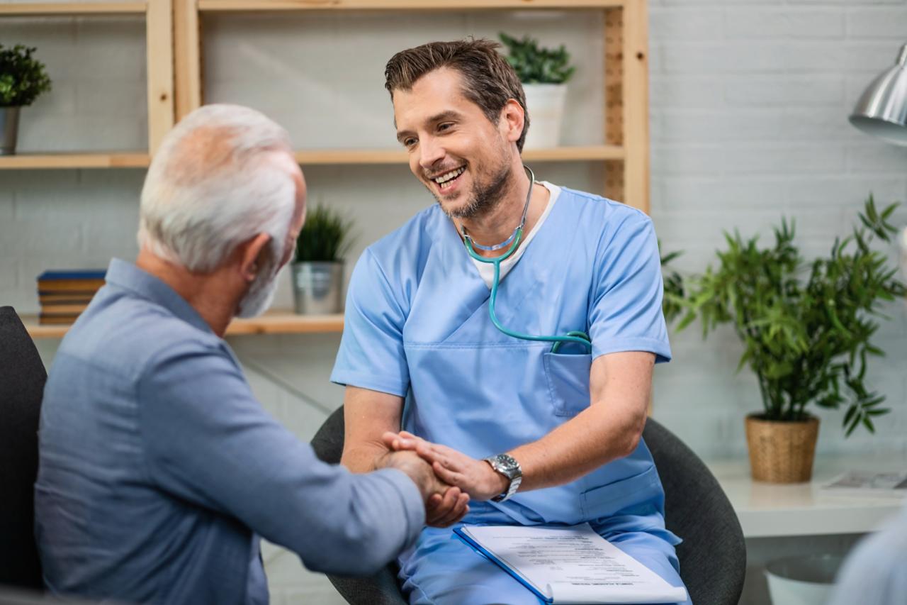 Infirmier en consultation avec un patient âgé et sa famille dans un cadre chaleureux à domicile